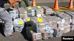FILE - Costa Rican police officers guard about two tons of cocaine in this handout photo provided by Costa Rica's Ministry of Public Security, Feb. 1, 2012. A cocaine-smuggling operation at the international airport in San Juan, Puerto Rico, has led to 12 suspects being indicted.