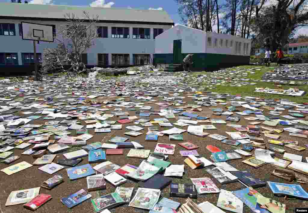 Paul Alexander Hatyay (tengah), kepala sekolah dan guru Central School, meletakkan buku-buku agar kering setelah atap perpustakaan sekolah tersebut ditiup oleh Siklon Pam di Port Vila, ibukota negara pulau Pasifik, Vanuatu. &nbsp;