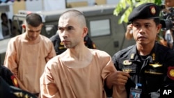 FILE - Police officers escort suspects in the blast at Erawan Shrine, Bilal Mohammad, front, and Mieraili Yusufu, rear, as they arrive at a military court in Bangkok, Thailand, Nov. 24, 2015.