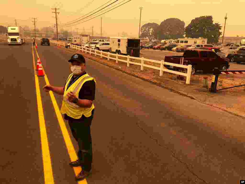 អ្នកធ្វើការស្ម័គ្រចិត្តកំពុងសម្រួលចរាចរណ៍ដល់ពលរដ្ឋដែលត្រូវបានជម្លៀសទៅកាន់កន្លែងសុវត្ថិភាពនៅ Oregon State Fairgrounds ក្រោមផ្ទៃមេឃគ្របដណ្តប់ដោយផ្សែងដែលបណ្តាលមកពីភ្លើងឆេះព្រៃនៅទីក្រុង Salem រដ្ឋ Oregon កាលពីថ្ងៃទី ៨ ខែកញ្ញា ឆ្នាំ២០២០។