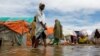 Warga menyeberangi air banjir di tempat penampungan sementara mereka di kamp Al-Hidaya untuk para pengungsi setelah hujan lebat di pinggiran Mogadishu, Somalia, 19 November 2023. (Foto: Reuters)