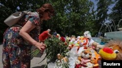 Seorang perempuan menaruh bunga di area memorial sementara di Sevastopol, Krimea, pada 24 Juni 2024. Memorial tersebut dibuat untuk mengenang korban dari serangan misil di Krimea, yang menurut otoritas Rusia dilakukan oleh Ukraina. (Foto: Reuters/Alexey Pavlishak) 