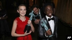 Millie Bobby Brown, kiri, dan Caleb McLaughlin memegang piala penghargaan untuk penampilan mereka dalam serial drama televisi “Stranger Things” di Screen Actors Guild Awards ke-23 di Shrine Auditorium & Expo Hall, 29 Januari 2017, di Los Angeles. 
