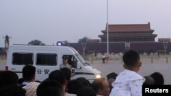 A paramilitary police officer stands guard in front of a police vehicle as people wait for the flag-raising ceremony held at Tiananmen Square during sunrise, in Beijing, China, June 4, 2019. 