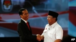 Calon presiden Indonesia Jokowi berjabat tangan dengan Prabowo Subianto sesudah acara debat presiden (15/6). Dalam masa kampanye presiden ini banyak terjadi kampanye hitam seperti misalnya penyebaran tabloid Obor Rakyat yang berisi fitnah terhadap Jokowi. 