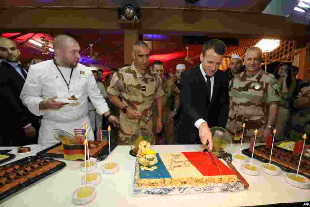 2017年12月22日,在尼亚美,法国总统马克龙与法国巴尔汗部队的大约700军人共进圣诞晚餐,他准备切蛋糕,蛋糕上有法国国旗的颜色。