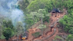 Pasukan etnis minoritas Karen terlihat setelah membakar sebuah bangunan di dalam pos militer Myanmar dekat perbatasan Thailand, yang terlihat dari sisi Thailand di Thanlwin (dikenal sebagai Salween), tepi sungai di provinsi Mae Hong Son, Thailand, 28 April 2021.

