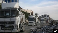 Truk-truk bantuan kemanusiaan masuk melalui penyeberangan Kerem Shalom dari Mesir ke Jalur Gaza, saat kesepakatan gencatan senjata antara Israel dan Hamas mulai berlaku, Minggu 19 Januari 2025.