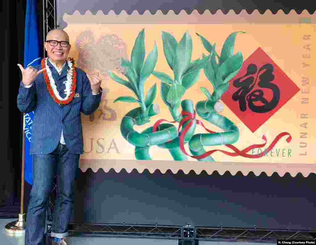 在夏威夷的火奴鲁鲁,被美国邮政选中而设计2008至2019农历新年系列邮票的美国华裔艺术家麦锦鸿 (Kam Mak) 站在他的最新作品——狗年邮票旁边。麦锦鸿说,他在邮票中突出了一些新年传统,“我决定在狗年邮票中使用三支竹子。在中国传统中,三支竹子意喻福、禄、寿。我还融入了手写福字。”