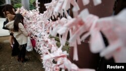 FILE - Visitors hang fortune blessing papers at Yasukuni Shrine in Tokyo, Dec. 26, 2013. 