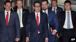 Menteri Keuangan AS Steven Mnuchin (tengah) dikawal oleh para pengawalnya dan delegasi meninggalkan hotel di Beijing, 29 Maret 2019.
