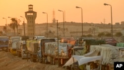 FILE - Trucks of humanitarian aids wait to cross the Rafah border crossing between Egypt and the Gaza Strip, in Rafah, Egypt, Sept. 9, 2024.