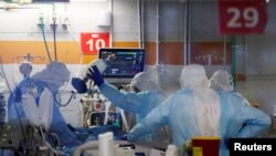 Pekerja medis, terlihat melalui jendela ruang observasi, mengenakan alat pelindung diri (APD) saat mereka bekerja di dalam bangsal bawah tanah yang merawat pasien COVID-19 di Unit Perawatan Kritis Coronavirus di Sheba Medica. (Foto: Reuters)