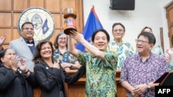 台湾总统府2024年12月5日拍摄和公布的照片显示台湾总统赖清德(右二)从关岛议长特拉耶(左二)手中接过木制欢迎礼物。