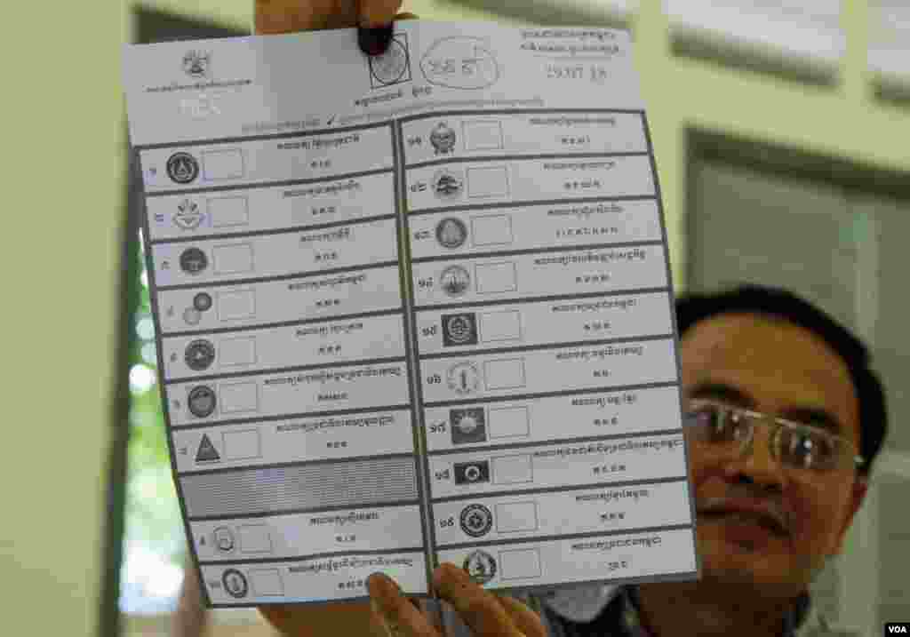 មន្ត្រីរៀបចំការបោះឆ្នោតលើកបង្ហាញសន្លឹកឆ្នោតមួយសន្លឹក​​ បន្ទាប់ពីការិយាល័យ​បោះឆ្នោតនៅទូទាំងប្រទេសបានបិទ នៅសង្កាត់បឹងកេង​កង២ ខណ្ឌ​ចំការមន រាជធានីភ្នំពេញ​ នៅ​ថ្ងៃអាទិត្យ​ ទី២៩ ខែកក្កដា​ ឆ្នាំ២០១៨។ (ខាន់ សុគុំមនោ/VOA)