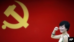 在上海的中共第一次代表大会会址，一名女子在中国共产党党旗下摆出宣誓姿势 （2012年7月1日）
