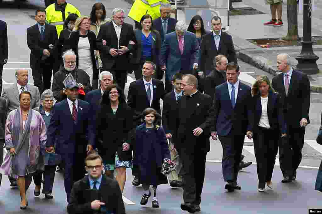 Family members of the victims of the 2013 Boston Marathon bombings are joined by Massachusetts Governor Deval Patrick (wearing a baseball cap, left) and Boston Mayor Marty Walsh (3rd right) as they walk to the finish line, April 15, 2014.