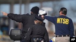 Seorang anggota Dewan Keselamatan Transportasi Nasional Amerika (NTSB) berbincang dengan petugas Kepolisian Philadelphia di lokasi kecelakaan pesawat kecil di Philadelphia, Sabtu, 1 Februari 2025. (Foto: Mat Rourke/AP)