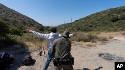 Foto ilustrasi yang menunjukkan seorang petugas perbatasan AS memeriksa seorang migran pencari suaka di dekat Dulzura, California, pada 5 Juni 2024. (Foto: AP/Gregory Bull)