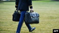 FILE - An aide carries nuclear codes to Marine One, the president's helicopter, on the South Lawn of the White House in Washington, Jan. 20, 2021. President Donald Trump left from there before Joe Biden's inauguration as president.