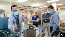 Ilustrasi. Astronot Kate Rubins, tengah, dan personel pendukung meninjau Sistem Pengelolaan Sampah Universal, toilet luar angkasa gravitasi rendah, di Houston, pada 18 Juni 2020 ini, foto disediakan oleh NASA. (Foto: AP)