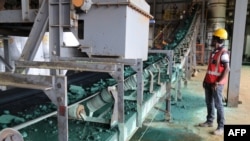 FILE - A man watches a conveyor belt loaded with chunks of raw cobalt after a first transformation at a plant in Lubumbashi, Congo, on Feb. 16, 2018, before being exported, mainly to China, to be refined.