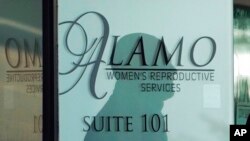 Senka radnika obezbeđenja na ulaznim vratima u Alamo servis za žensku reprodukciju, 7. oktobra 2021. u San Antoniju, u Teksas. (Foto: AP/Eric Gay)