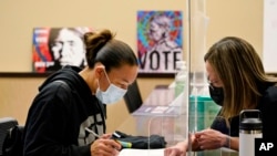 FILE - In this Nov. 3, 2020, photo, Lummi Tribal member Patsy Wilson, left, is assisted by Lummi Native Vote Team 2020 volunteer Kelli Jefferson in voting on the Lummi Reservation, near Bellingham, Wash.