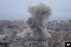 FILE - Asap mengepul di antara gedung-gedung yang terkena serangan udara Israel di Dahiyeh, di pinggiran selatan Beirut, Lebanon, 17 November 2024.