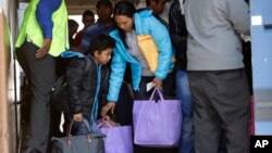 FILE - Immigrants from Central America seeking asylum board a bus, April 2, 2019, in downtown San Antonio.