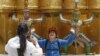 FILE - A Chinese tourist strikes a similar pose to statues as they visit the Grand Palace in Bangkok.