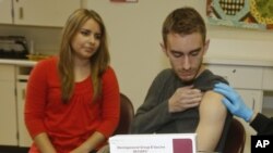 FILE - Meningococcal meningitis survivor and vaccination advocate Leslie Meigs looks on as her brother Andrew (18), a college student in Texas, receives Bexsero(R), a meningococcal group B vaccine approved by the FDA for ages 10-25. 