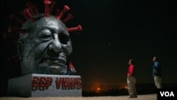 雕塑家陈维明和苏立德站在他们的作品“中共病毒”前（美国之音记者文灏拍摄）