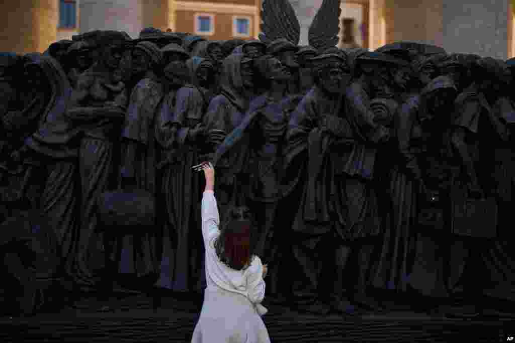 A girl touches the &quot;Angels Unaware&quot; boat sculpture by Canadian artist Timothy P. Schmalz placed at St. Peter&#39;s square in Rome.