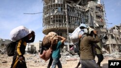FILE - Displaced Palestinians carry their belongings as they walk amid the devastation upon their return to central Rafah in the southern Gaza Strip on Jan. 19, 2025, after a ceasefire between Israel and the Hamas movement took effect.