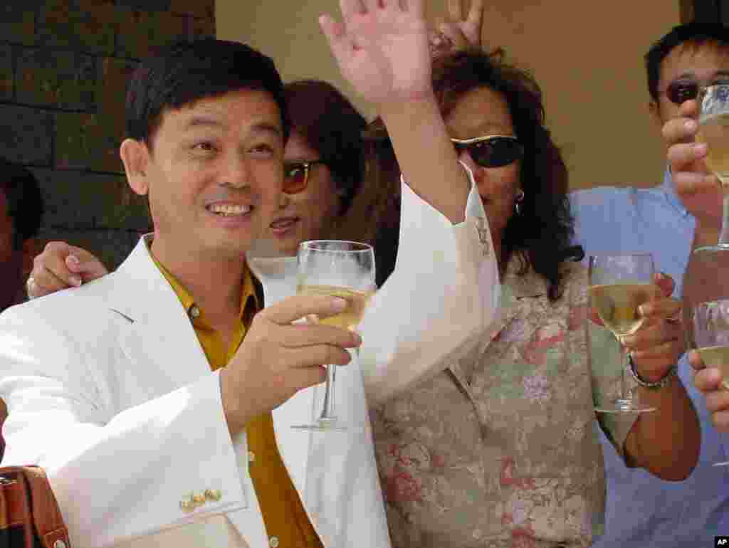 在关岛的美国移民局办公室前面,中国的气功组织“中功”的创始人张宏宝在获得假释后举杯庆贺(2001年4月17日),随后他获得美国政治庇护。2001年2月,张宏堡持伪造证件逃到关岛,被拘押。美中两国在处理张宏堡问题上一度相持不下。中国的海外异议人士游说美国国会,要求将张宏堡留在美国。