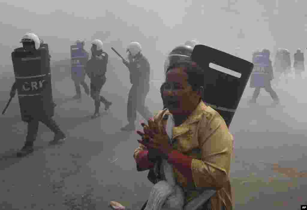 A protester moves away from riot police officers who fire tear gas grenades during a protest in Phnom Penh, Jan. 27, 2014.