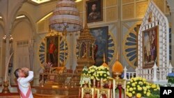 FILE - In this photo released by Bureau of the Royal Household, Thailand 's new king Maha Vajiralongkorn Bodindradebayavarangkun pays his respects to a portrait of the late Thai King Bhumibol Adulyadej and Thai Queen Sirikit at the Dusit Palace Dec.1, 2016.