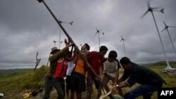 Warga menegakkan kincir angin di lapangan turbin angin kecil di desa di Pulau Sumba, Nusa Tenggara Timur. (Foto: AFP)