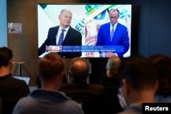 2025년 2월 19일 독일 베를린에서 언론인들이 TV를 통해 중계되는 사회민주당(SPD) 총리 올라프 숄츠와 그의 보수적 경쟁자인 기독교민주연합(CDU) 프리드리히 메르츠의 토론을 지켜보고 있다.