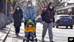 Majke sa decom sa maskama na licu šetaju na ulici u Pekingu (AP Photo/Andy Wong)